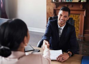 Two adults reviewing divorce documents and financial records at a kitchen table with a calendar and folders nearby.