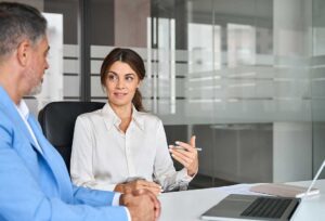 Two adults review divorce papers and a parenting calendar at a table with folders and financial documents.